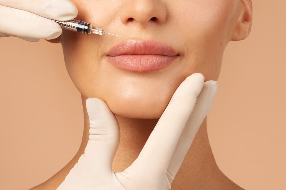 lower half of woman's face with needle approaching upper lip