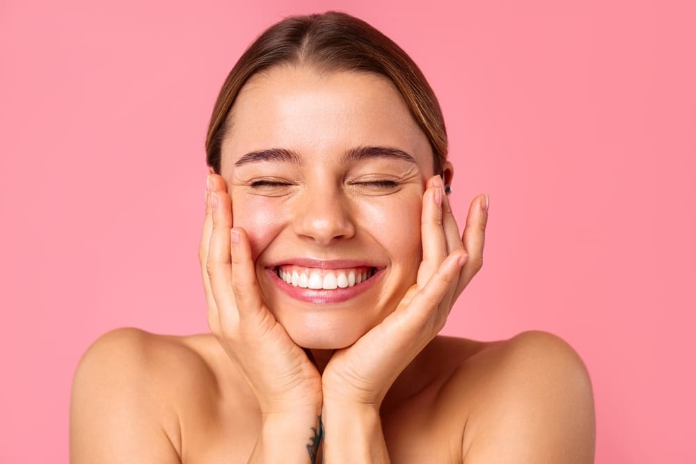 Woman with hands on sides of face smiling widely
